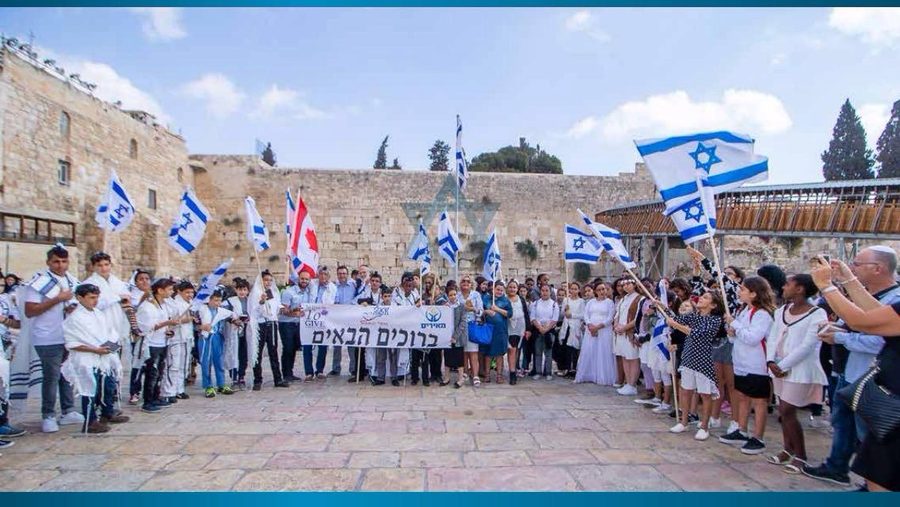 Full B'nai Mitzvah ceremony group at the Western Wall with Israeli flags